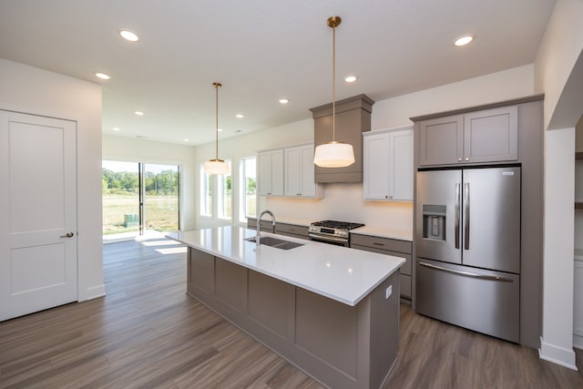 kitchen featuring an island with sink, sink, gray cabinetry, dark hardwood / wood-style flooring, and stainless steel appliances