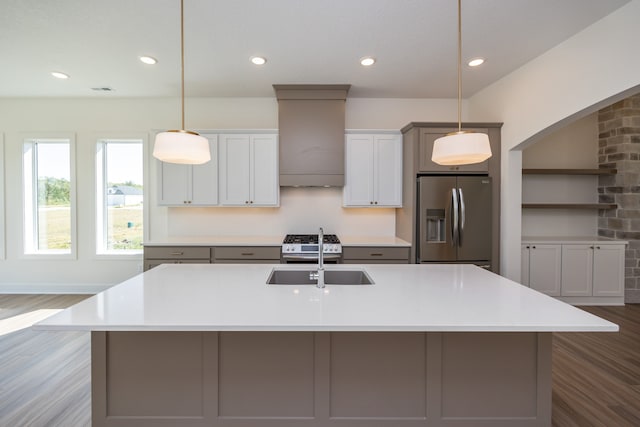 kitchen featuring stainless steel appliances, sink, pendant lighting, and wall chimney exhaust hood