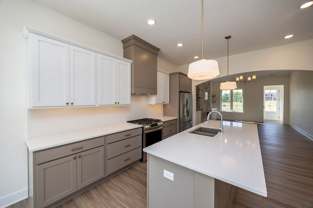 kitchen with sink, decorative light fixtures, appliances with stainless steel finishes, an island with sink, and hardwood / wood-style floors