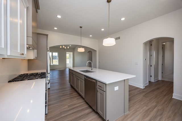 kitchen with decorative light fixtures, dishwasher, sink, dark wood-type flooring, and a center island with sink