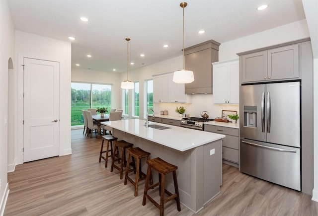 kitchen with an island with sink, recessed lighting, a sink, light wood finished floors, and stainless steel appliances