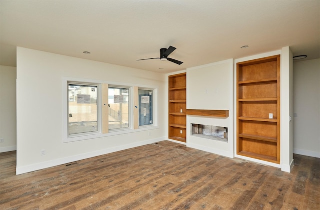 unfurnished living room featuring visible vents, baseboards, a fireplace with raised hearth, ceiling fan, and dark wood-type flooring