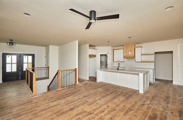 kitchen with tasteful backsplash, a center island with sink, wood finished floors, light countertops, and open shelves