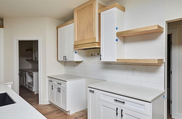 kitchen with wood finished floors, white cabinets, light countertops, custom exhaust hood, and decorative backsplash