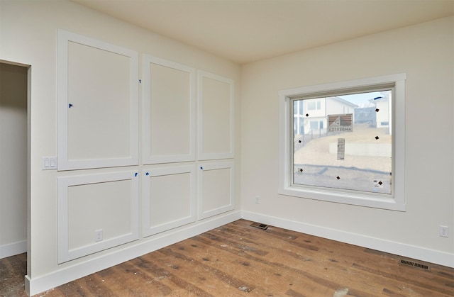 empty room with baseboards, visible vents, and dark wood-style flooring