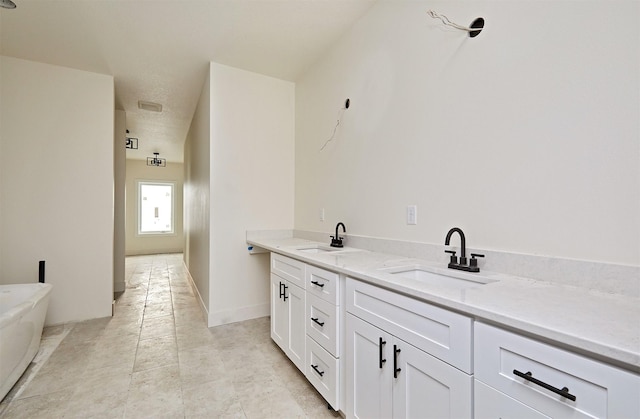 full bathroom with a freestanding tub, a sink, baseboards, and double vanity