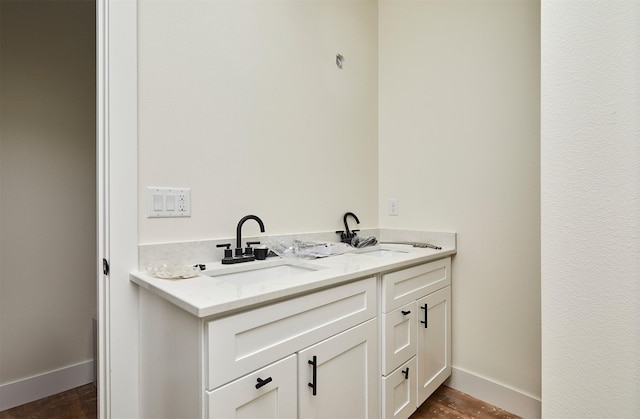 bathroom featuring double vanity, a sink, and baseboards