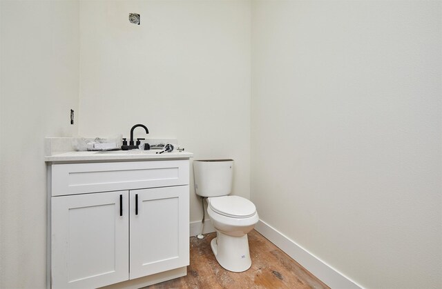 half bath featuring toilet, baseboards, wood finished floors, and vanity