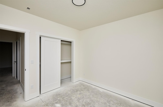 unfurnished bedroom with baseboards, a closet, and unfinished concrete floors