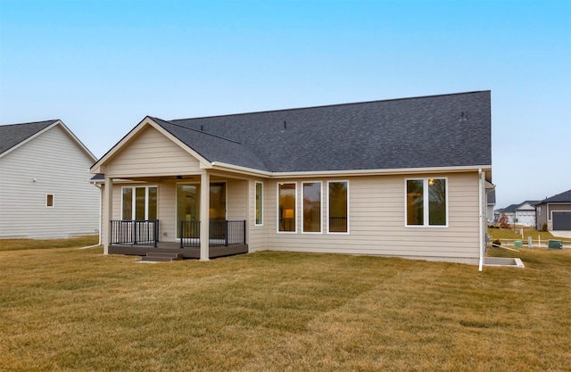 back of property featuring a lawn and a deck