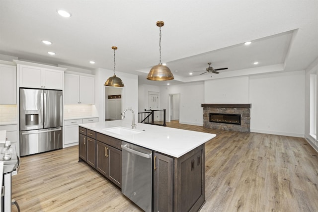 kitchen with decorative backsplash, stainless steel appliances, sink, a fireplace, and hanging light fixtures