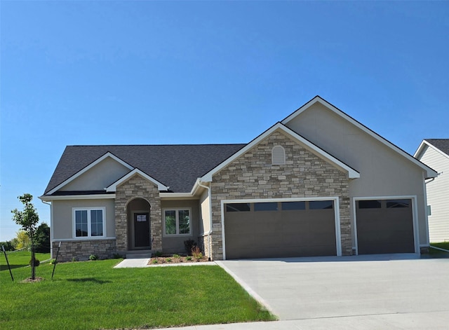 16300 Goodman Dr, Urbandale, IA 50323 - view of front facade with stone siding, a garage, driveway, a front yard, and stucco siding