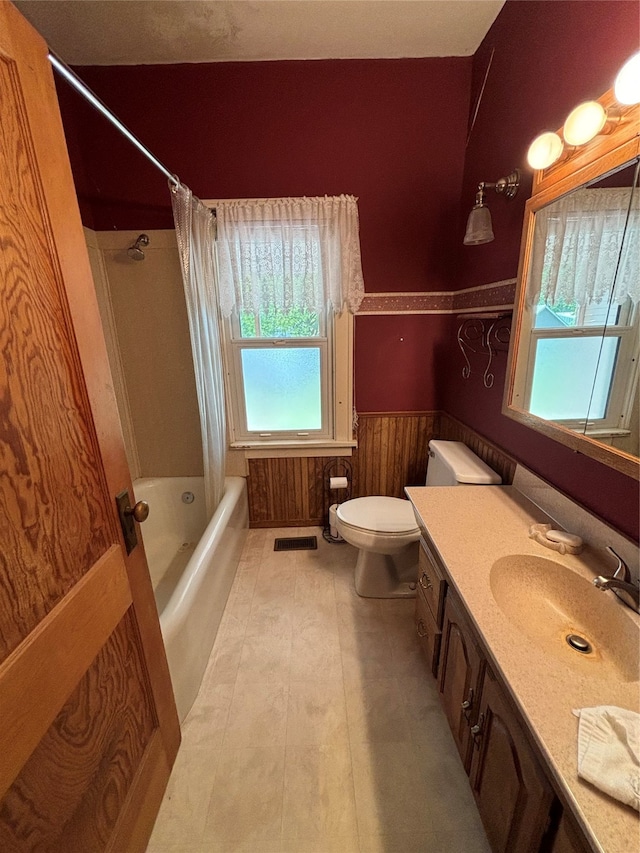 full bathroom with wood walls, tile patterned floors, shower / tub combo with curtain, vanity, and toilet