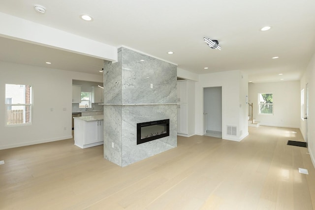 unfurnished living room with a premium fireplace, sink, and light wood-type flooring