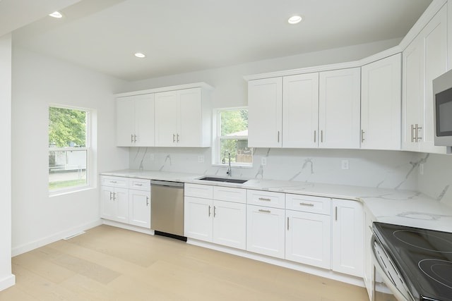 kitchen with appliances with stainless steel finishes, sink, white cabinets, backsplash, and plenty of natural light