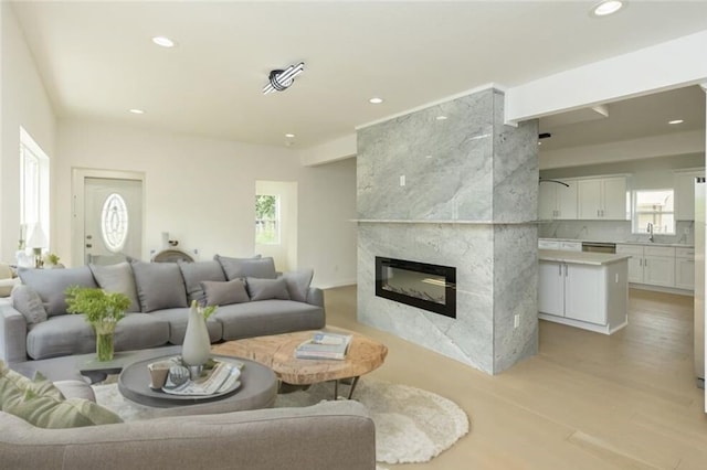 living room featuring sink, a fireplace, and light hardwood / wood-style flooring