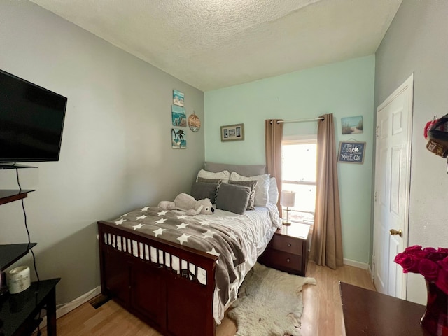 bedroom with a textured ceiling and light hardwood / wood-style flooring