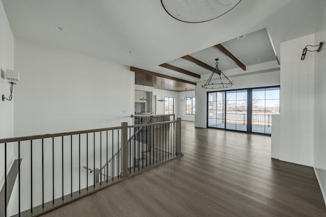 spare room with an inviting chandelier, dark hardwood / wood-style floors, and beamed ceiling