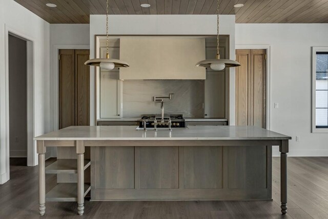 kitchen featuring wooden ceiling, dark hardwood / wood-style floors, pendant lighting, a large island with sink, and sink