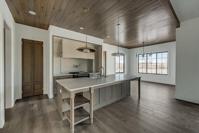 kitchen with decorative light fixtures, dark wood-type flooring, an inviting chandelier, an island with sink, and sink