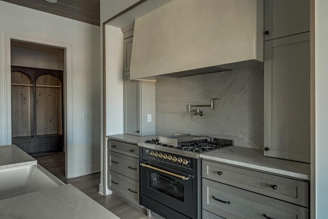 kitchen with gray cabinets, range with gas cooktop, tasteful backsplash, and custom range hood