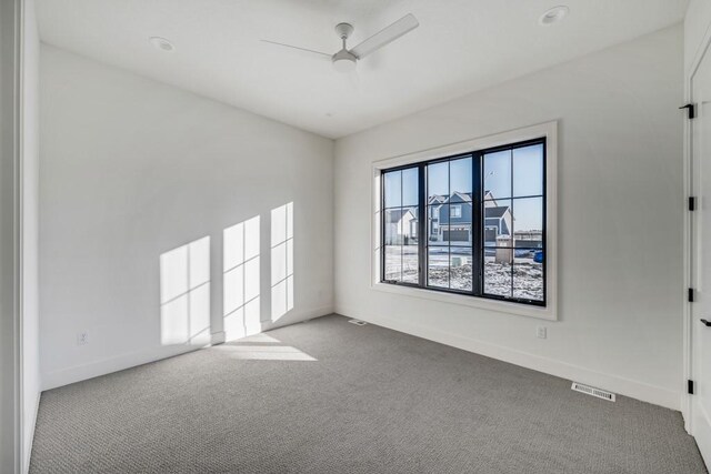 carpeted spare room featuring ceiling fan