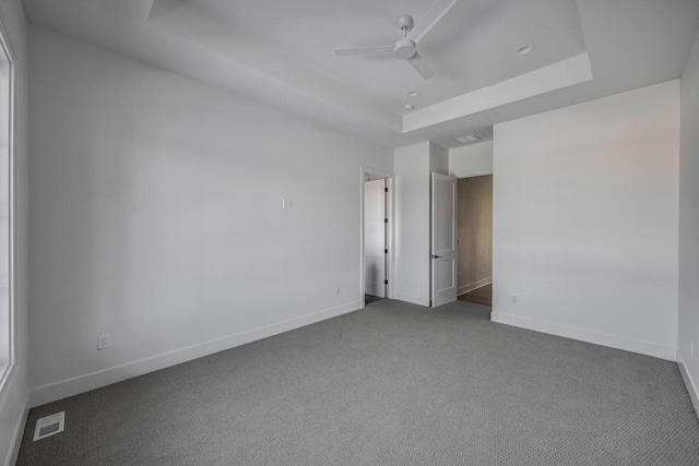 carpeted empty room featuring ceiling fan and a tray ceiling