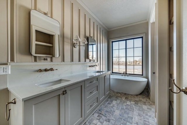 bathroom featuring vanity, a bathing tub, crown molding, and a textured ceiling