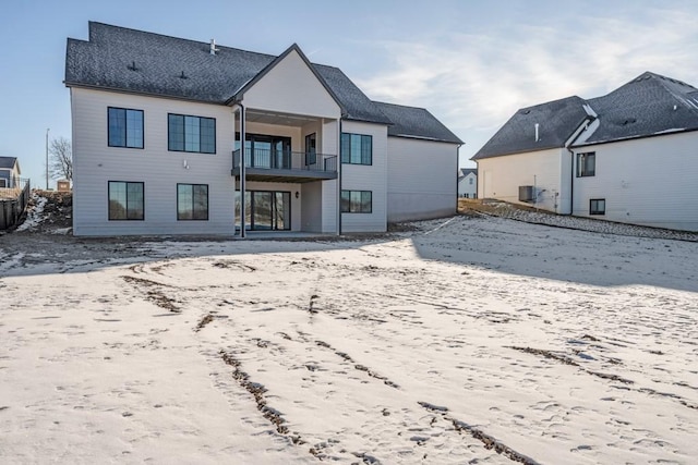 snow covered house featuring a balcony and cooling unit