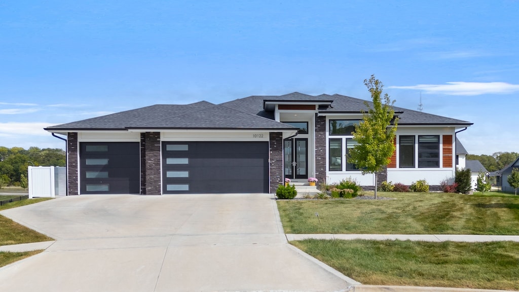 prairie-style home featuring a front lawn and a garage