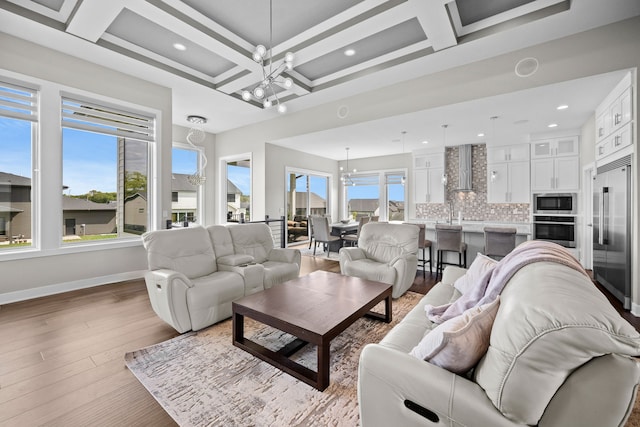 living room with beam ceiling, light hardwood / wood-style flooring, coffered ceiling, and a notable chandelier