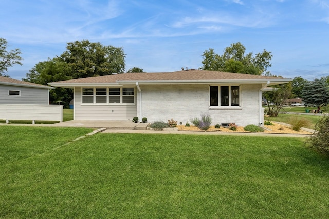 back of house with brick siding and a yard