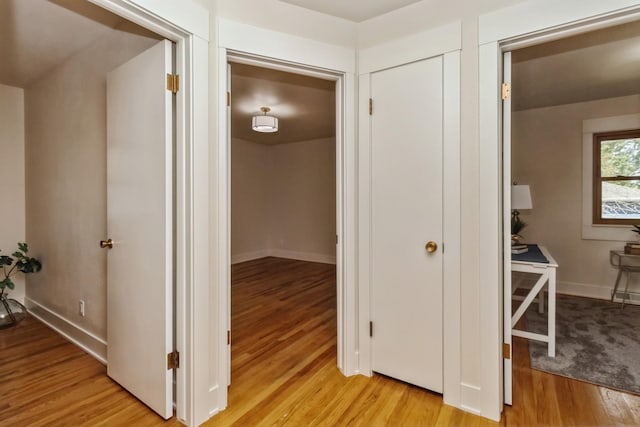 hallway featuring light wood-style flooring and baseboards