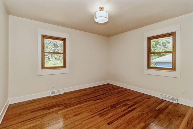 empty room with hardwood / wood-style flooring and plenty of natural light