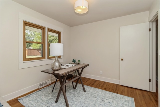 office area with baseboards, wood finished floors, and visible vents
