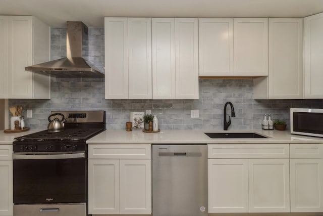 kitchen with tasteful backsplash, white cabinets, wall chimney exhaust hood, stainless steel appliances, and sink