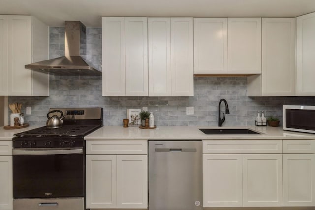kitchen with wall chimney range hood, stainless steel appliances, light countertops, and a sink