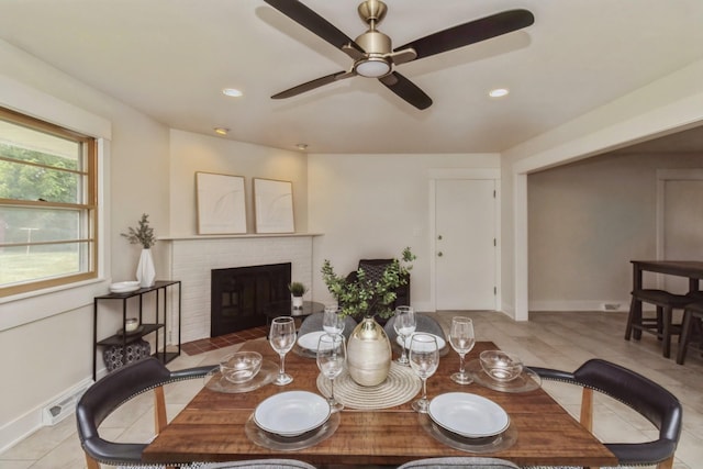 tiled dining area with a ceiling fan, baseboards, a brick fireplace, visible vents, and recessed lighting
