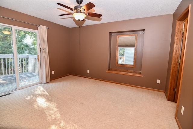 empty room with ceiling fan, light carpet, and a textured ceiling