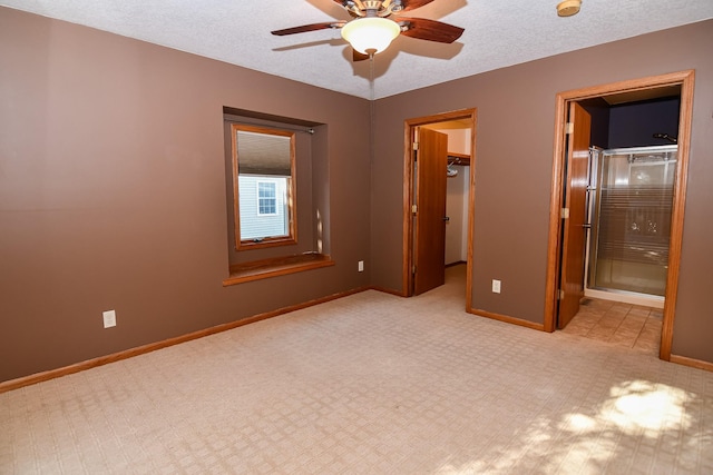 unfurnished bedroom featuring a textured ceiling, ceiling fan, a spacious closet, connected bathroom, and a closet