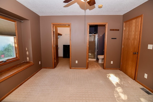 unfurnished bedroom featuring a walk in closet, ensuite bathroom, a textured ceiling, ceiling fan, and a closet