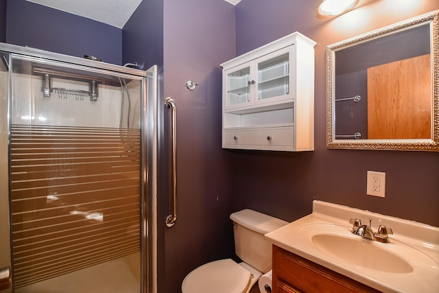 bathroom with vanity, toilet, and a shower with door