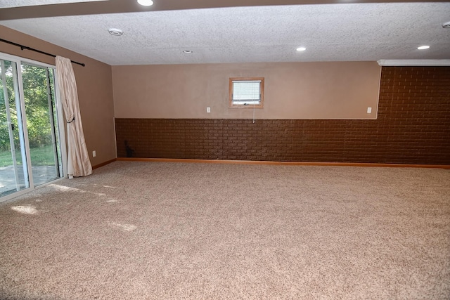 spare room with carpet, a textured ceiling, and brick wall