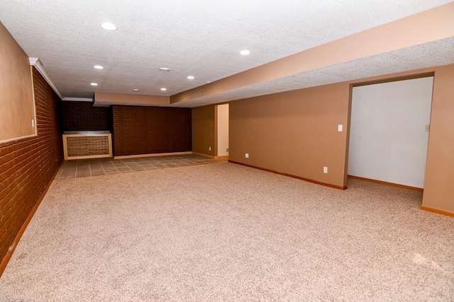 basement with carpet flooring, brick wall, and a textured ceiling