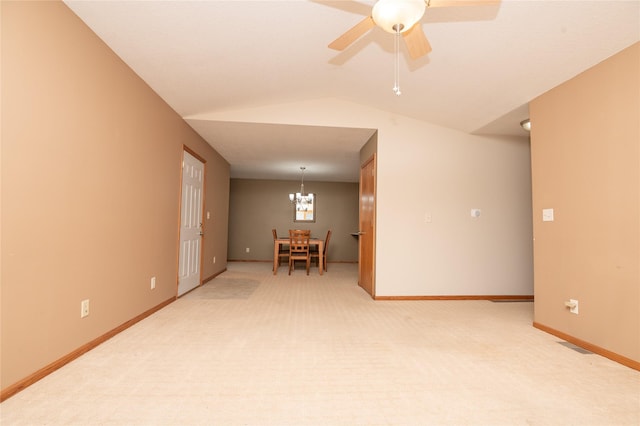 carpeted empty room featuring ceiling fan with notable chandelier and lofted ceiling