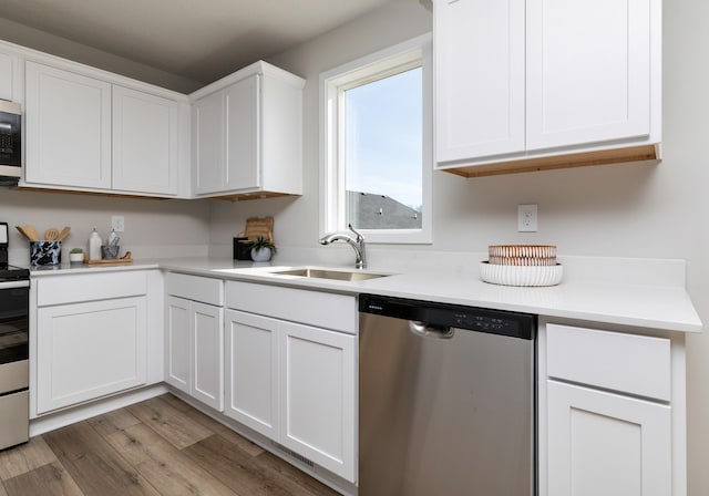 kitchen with white cabinets, appliances with stainless steel finishes, hardwood / wood-style flooring, and sink