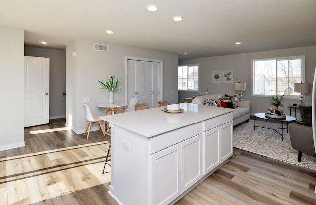 kitchen featuring a kitchen island, a breakfast bar area, plenty of natural light, and white cabinetry