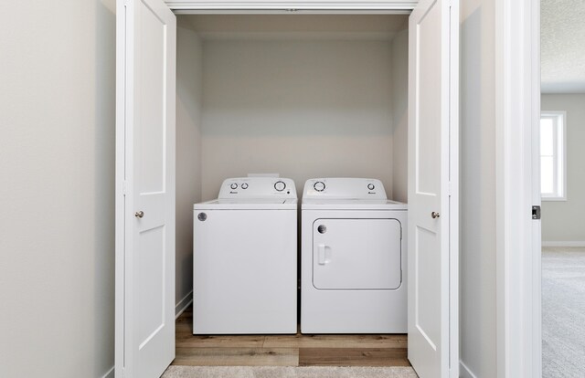 clothes washing area with light hardwood / wood-style flooring, a textured ceiling, and washing machine and dryer