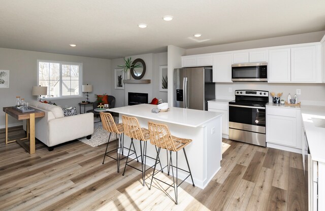 kitchen featuring white cabinets, appliances with stainless steel finishes, light hardwood / wood-style flooring, and a kitchen island