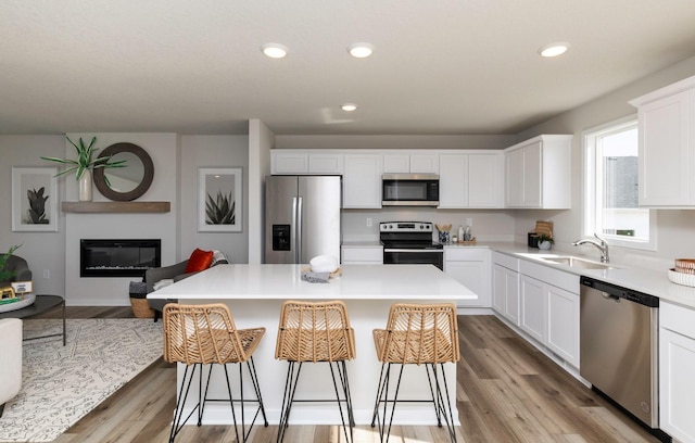 161 NE 56th St, Pleasant Hill, IA 50327 - kitchen featuring stainless steel appliances, a sink, white cabinets, a breakfast bar area, and light countertops